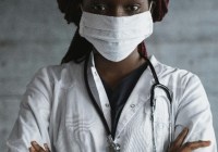 Image of Black or African American Female Clinician in a White Lab Coat Wearing a Mask and Stethascope