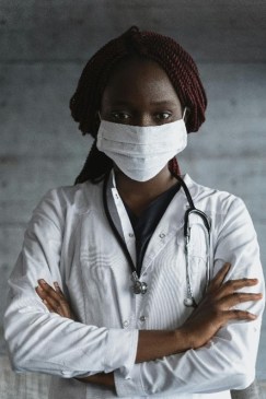 Image of Black or African American Female Clinician in a White Lab Coat Wearing a Mask and Stethascope