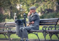 Older adult on park bench with facemask