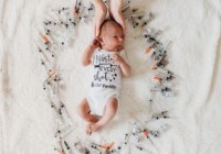 Image of infant surrounded by IVF injection needles, with two hands cradling the head