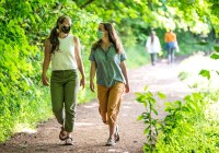 Two women walking while wearing pandemic masks