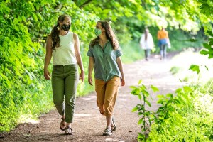 Two women walking while wearing pandemic masks