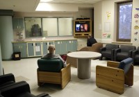 Two patients sitting in a common area of a psychiatric ward, watching television