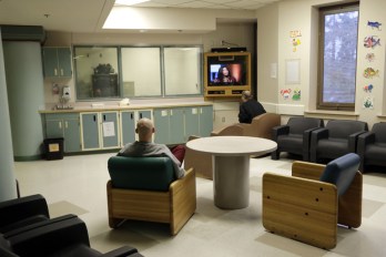 Two patients sitting in a common area of a psychiatric ward, watching television. This is used to show the risks of inpatient psychiatry