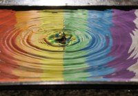 Splash of water rippling outward on a rainbow background