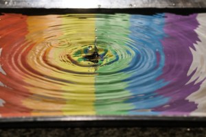 Splash of water rippling outward on a rainbow background